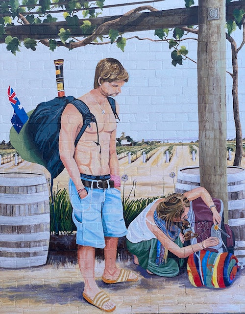 two backpackers sorting out their daypacks whilst exploring a winery with vines and the vineyard in the background